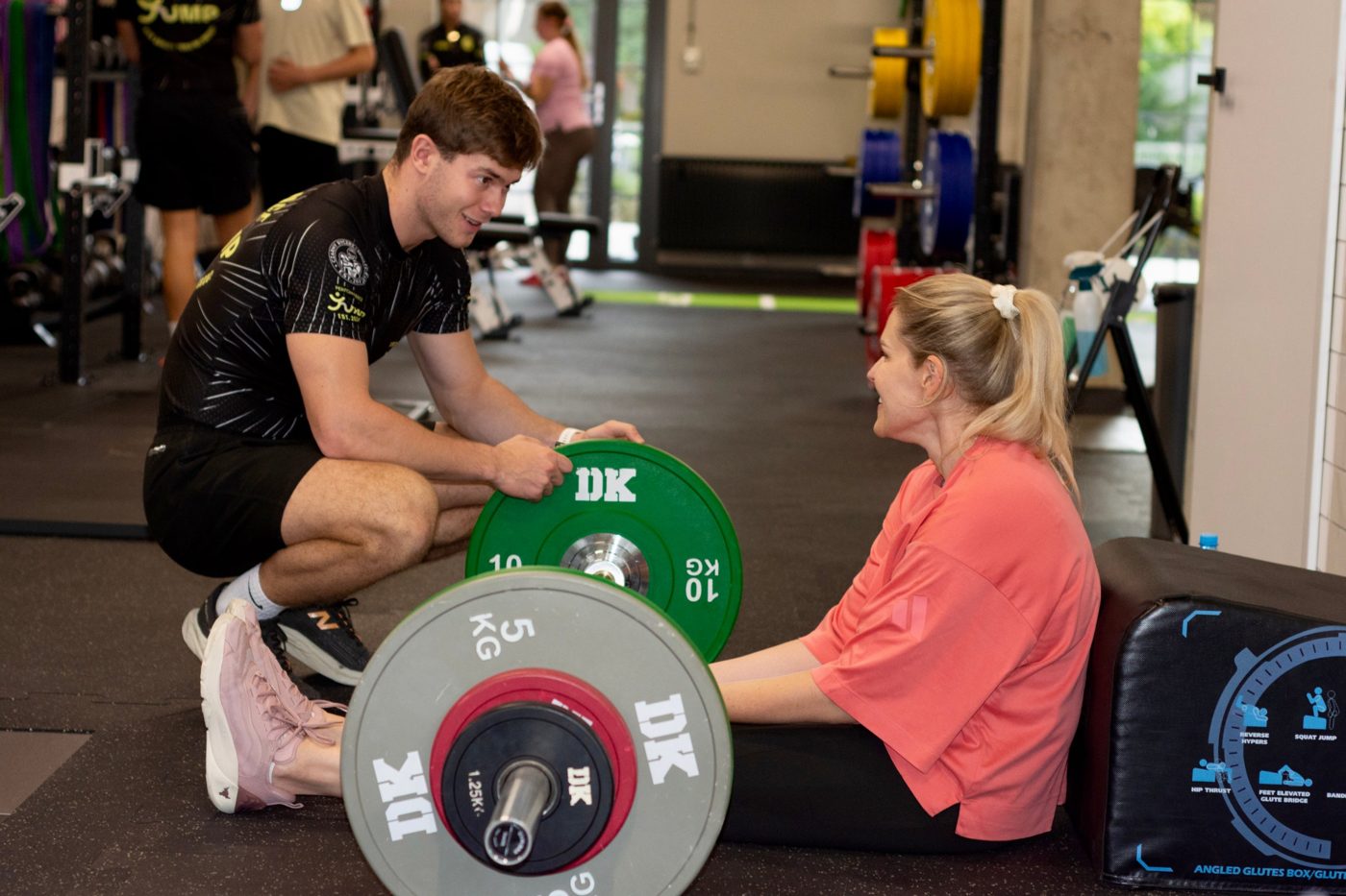 Trener przygotowuje hip thrust z podopieczną